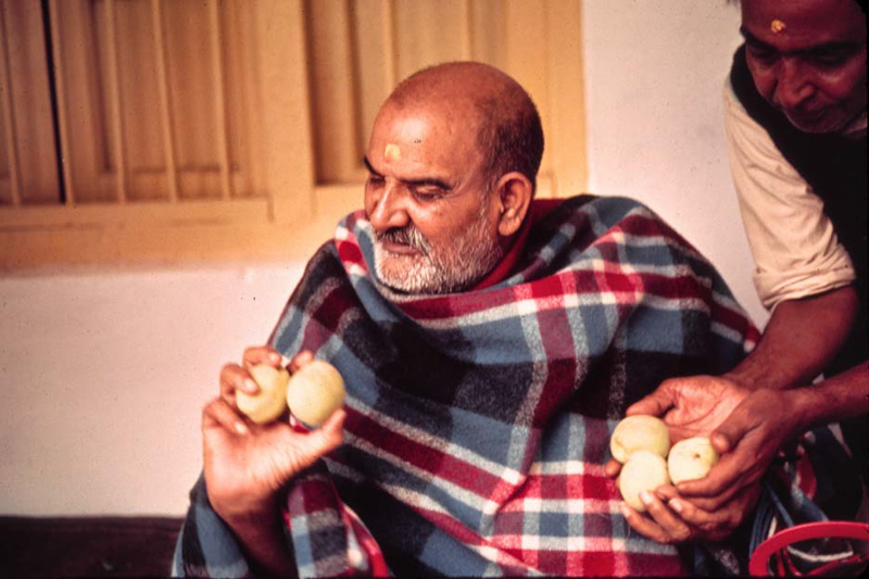 Baba verteilt Äpfel, Prasad - rechts im Bild ist Dada Mukherjee, der Ihm mehr Äpfel in die freie Hand legt